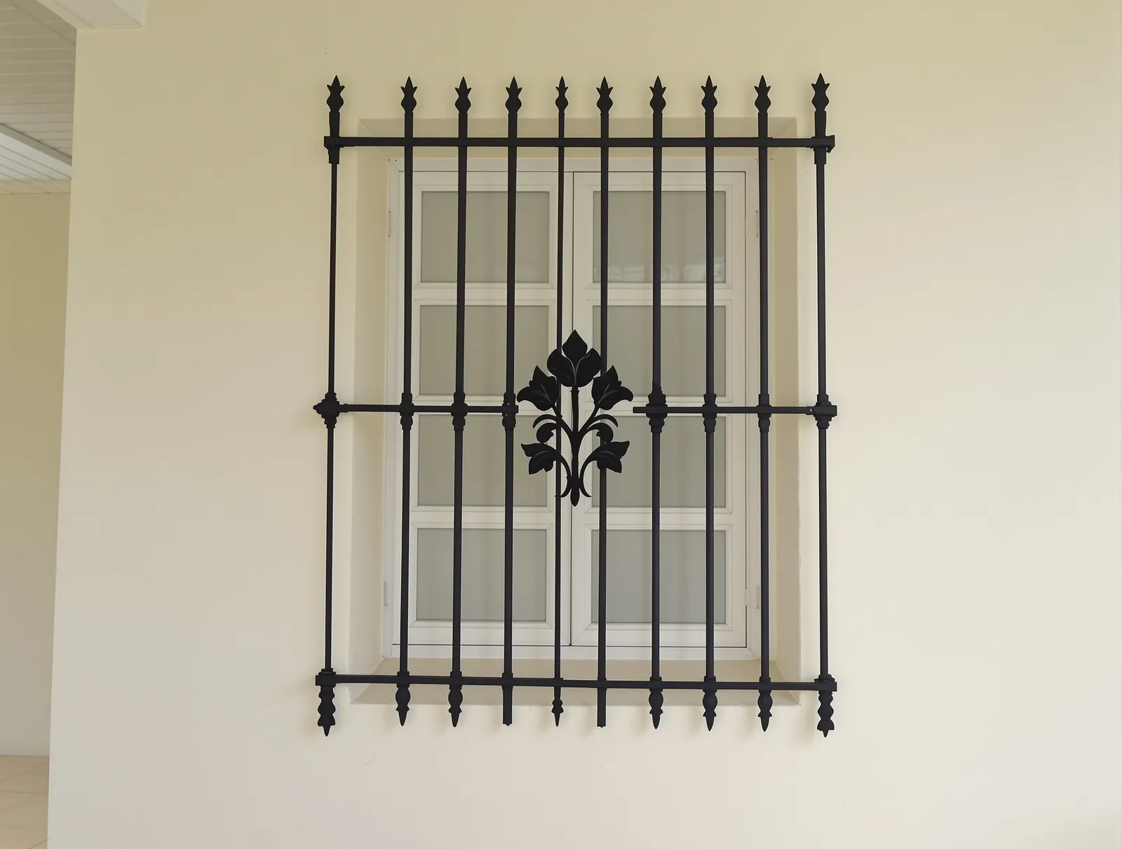 Black window grill with a flower ornament in the centre and spear tops
