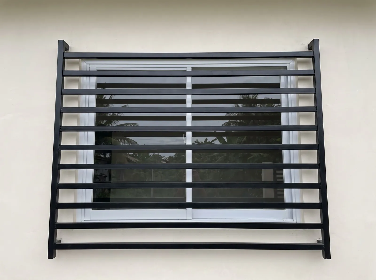 Modern black steel window grill of horizontal flat bars over a white sliding window