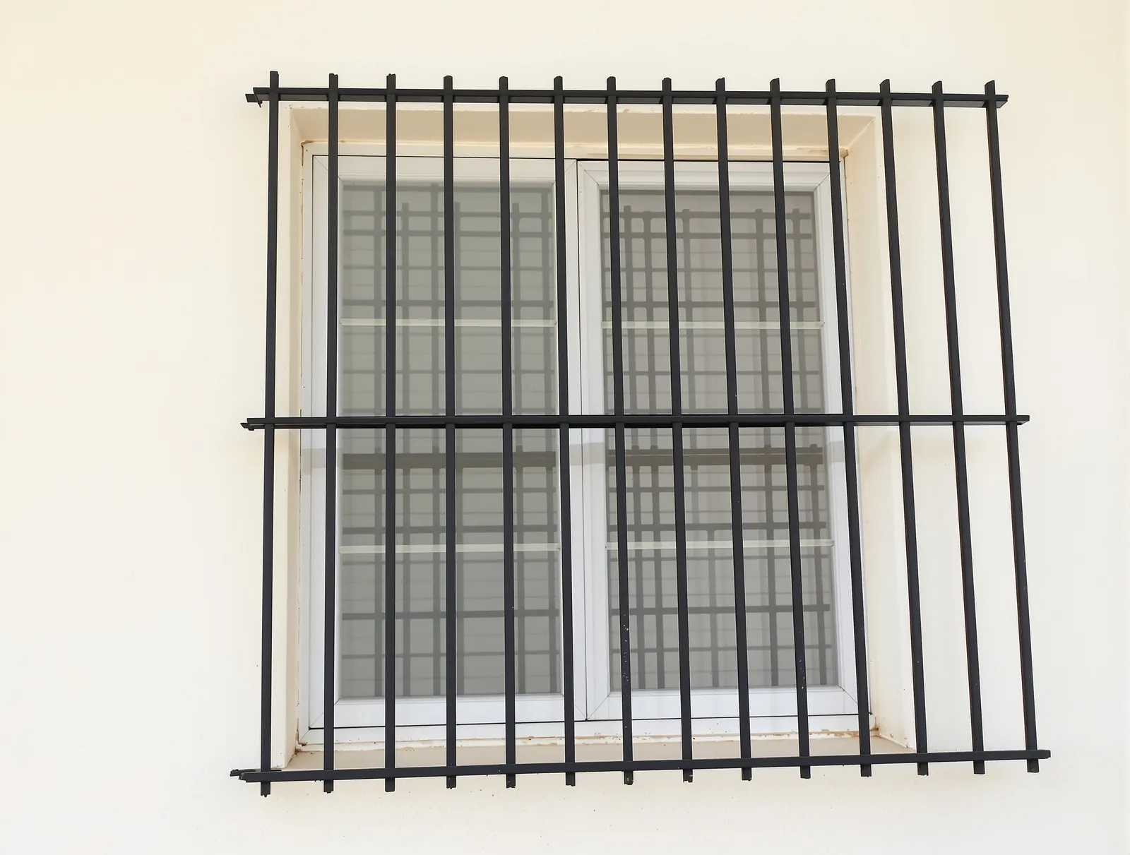 Black window grill of vertical square bars with one middle bar